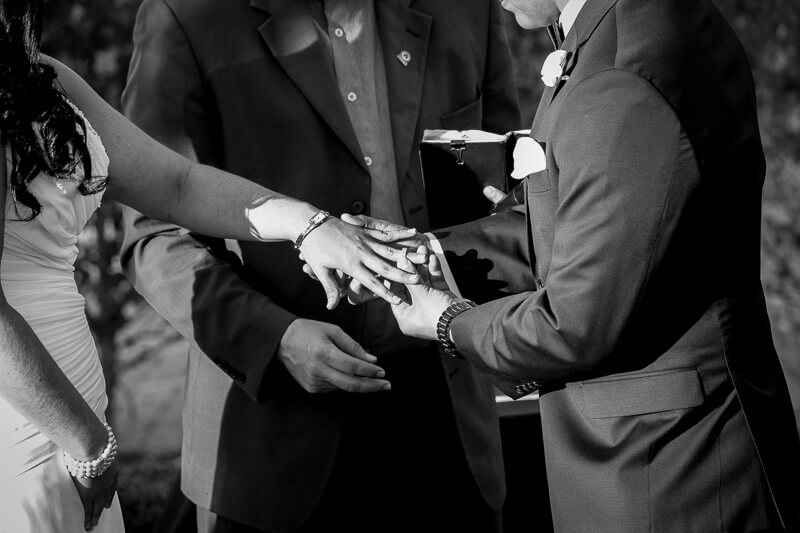 wedding photo of groom putting ring on bride